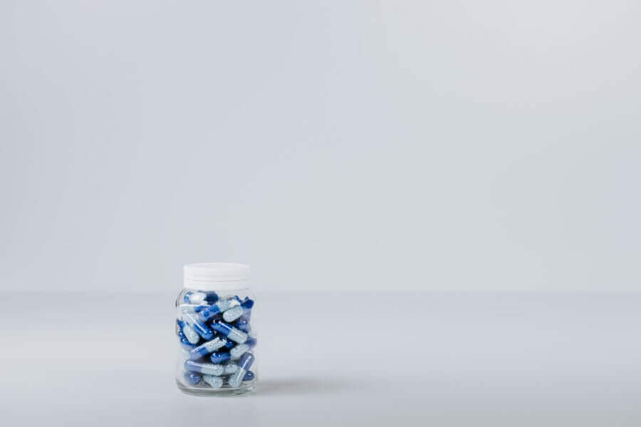 A bottle of blue prescription drug capsules.