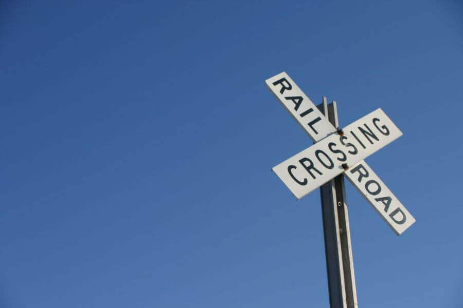 Railroad crossing sign with blue sky background.